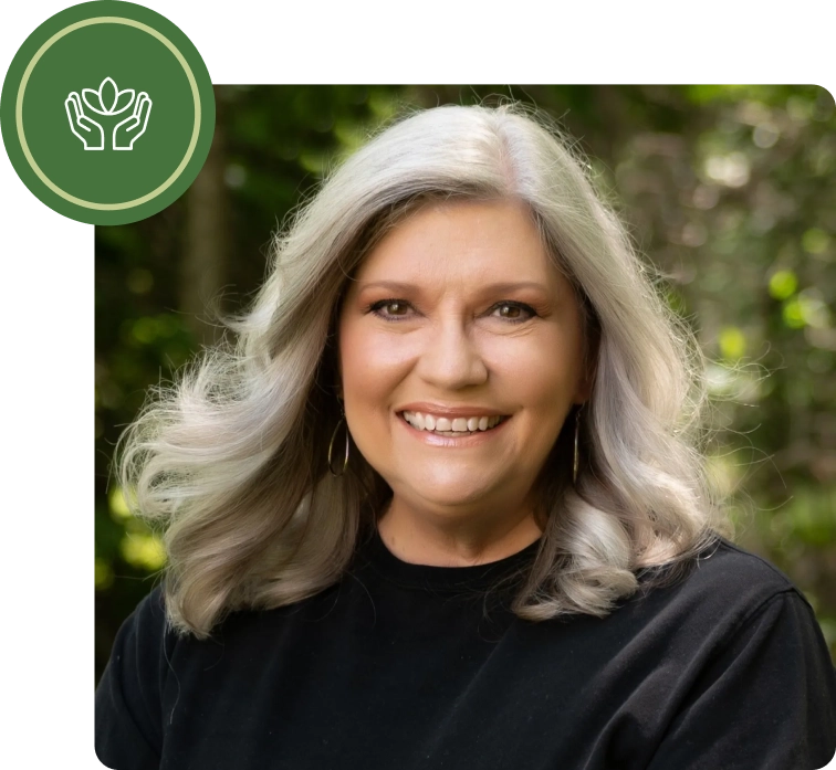 A woman with long gray hair is smiling.